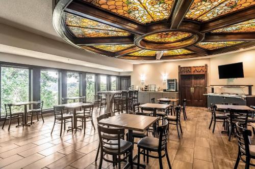 un restaurant avec des tables et des chaises et un plafond en vitraux dans l'établissement Riverview Inn & Suites, an Ascend Collection Hotel, à Rockford