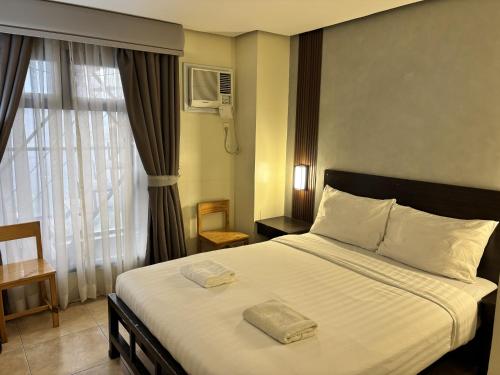 a bedroom with a bed with two towels on it at kasa Boutique Hotel Capitol in Cebu City
