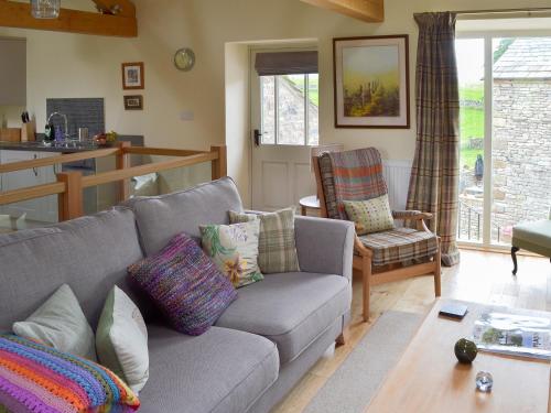 a living room with a couch and a kitchen at Brow View Cottage in Ravenstonedale
