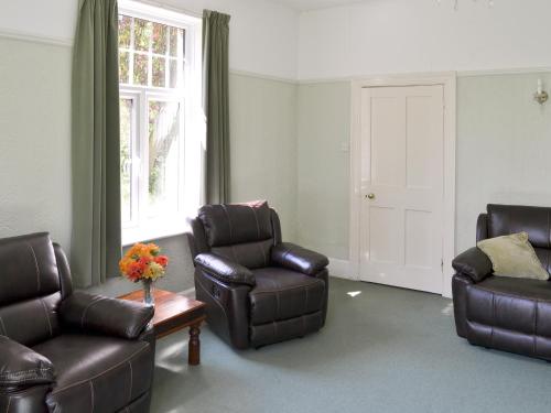 een woonkamer met lederen meubels en een raam bij Bridge End - E1028 in Waxham