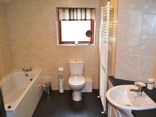 a bathroom with a toilet and a tub and a sink at Wickhams View in Keswick