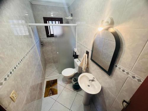 a bathroom with a toilet and a sink and a mirror at Medeiros in Capão da Canoa