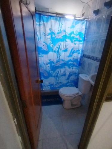 a bathroom with a toilet and a blue shower curtain at Hotel mi casita in Bogotá