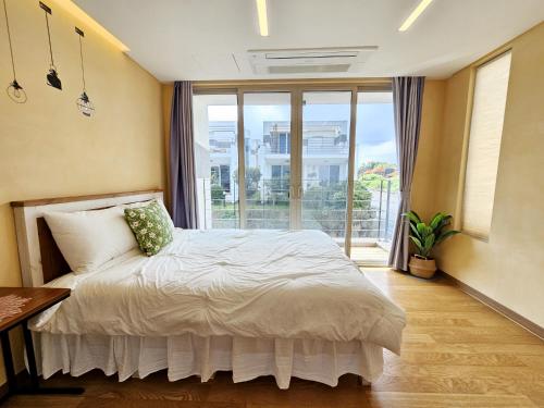 ein Schlafzimmer mit einem Bett und einem großen Fenster in der Unterkunft Aewol Penthouse in Jeju-do
