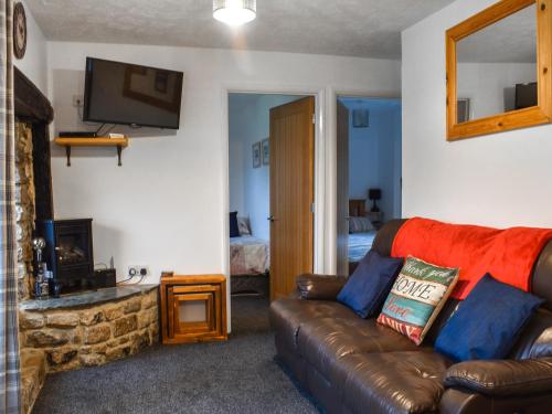 Culver Cottage - Uk48987 في لوي: غرفة معيشة مع أريكة جلدية ومدفأة