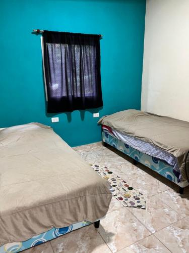 two beds in a room with a blue wall at Alojamiento MD in Wanda