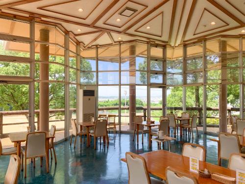a dining room with tables and chairs and windows at 芸西村の家 in Geisei