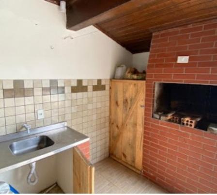 a kitchen with a sink and a brick wall at Casas em frente ao mar com piscina, churrasqueira in Pontal do Paraná