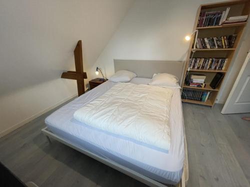 1 dormitorio con 1 cama con sábanas blancas y estante para libros en Maison calme pour 10 pers, proche plage, Port Navalo, animaux admis, wifi - FR-1-775-42, en Port-Navalo