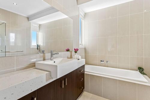 een badkamer met een wastafel, een bad en een spiegel bij Sorrento City Style in Sorrento