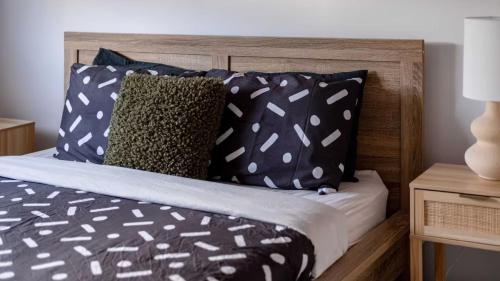 a bed with black and white pillows and a wooden headboard at The Robinson in Connewarre