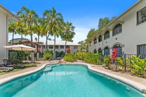 a swimming pool in front of a building with palm trees at Palm Cove Studio Pools Spa Bar in Palm Beach