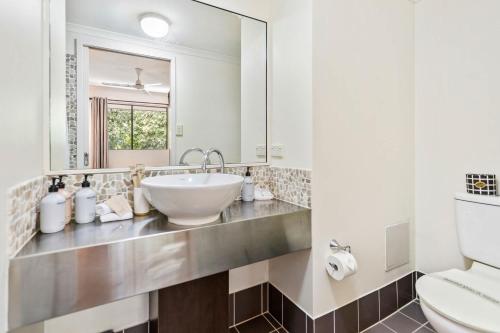 a bathroom with a sink and a mirror at Palm Cove Studio Pools Spa Bar in Palm Beach