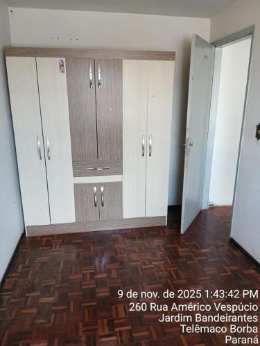 een kamer met witte kasten en houten vloeren bij Kitnet na Band in Telêmaco Borba