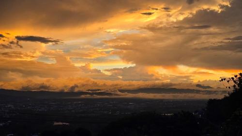 a sunset with clouds in the sky over a city at Hotel Mirador Mayday Mountain View in Alajuela City
