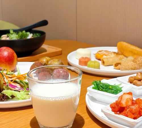 uma mesa com pratos de comida e um copo de leite em Xi'an MC City Courtyard Hotel - A st andalone hotel by the city wall - Close to the bell tower and yongning gate - Designed in song dynasty aesthetic style - It features private courtyard and garden rooms - Integrating the historical culture of Xi'an em Xian