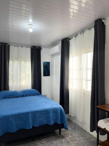 a bedroom with a bed with blue sheets and curtains at Casa Onca in Río Claro