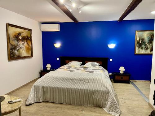 een blauwe slaapkamer met een bed en een blauwe muur bij Escapade dans la campagne toulousaine in Beaumont-sur-Lèze