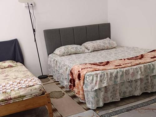 a bedroom with two beds and a lamp at Roomstay Ummi in Macang