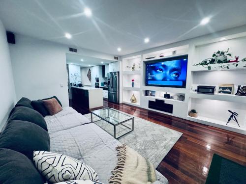 a living room with a couch and a flat screen tv at Luxe Riverside Oasis 3BR for 6 Guests Home Near Flemington Racecourse 16 min to CBD 20 min to Airport 2 mins walk to Public Transport to go to Train Station and Highpoint Shopping Centre in Melbourne