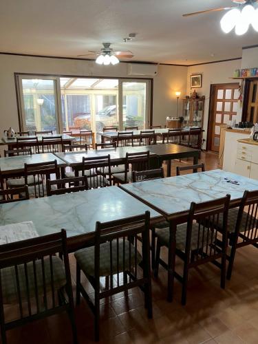 a dining room with tables and chairs and windows at Resort inn Sakanoshita in Fujikawaguchiko