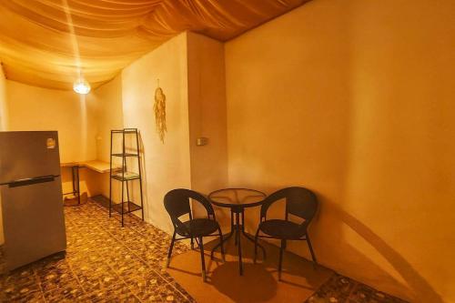 Habitación con mesa, sillas y nevera. en Starlight Bungalows - 3 Mins Walk To Beach, en Ko Lanta Yai