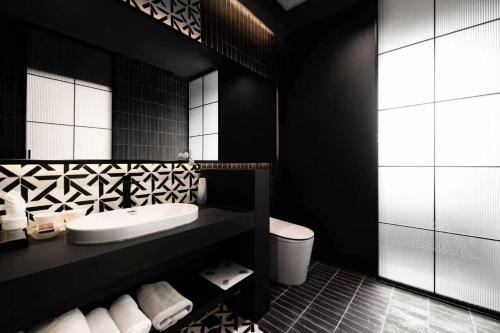 a black bathroom with a sink and a toilet at 烟台朝阳文保艺术酒店 in Yantai