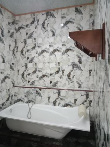 a bath tub in a bathroom with a marble wall at Theresia Bin Cottage in Ngurblut