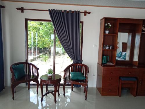 ein Zimmer mit zwei Stühlen und einem Tisch und einem Fenster in der Unterkunft Theresia Bin Cottage in Ngurblut