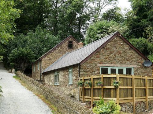 a stone house with a wooden fence and a building at Burrills View in Horderley