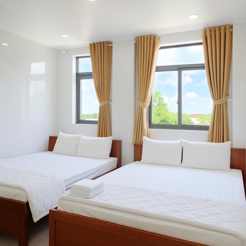 two beds in a room with windows at Bảo Di Sóc Trăng Hotel in Soc Trang