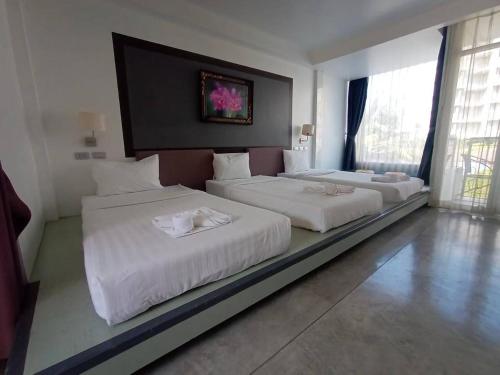 a hotel room with two beds with white sheets at Sunset Serenity Jomtien Resort in Na Jomtien
