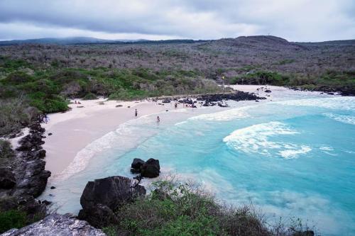 a beach with people on the sand and water at Cabañas Don Jorge - Cabaña Fragata in Puerto Baquerizo Moreno