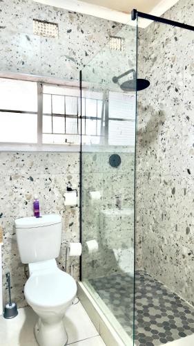a bathroom with a toilet and a glass shower at CityStay - Studio Apartment in East London