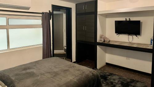 a bedroom with a bed and a flat screen tv at SUITE 5 Del Centro de Cuauhtémoc Chihuahua in Cuauhtémoc