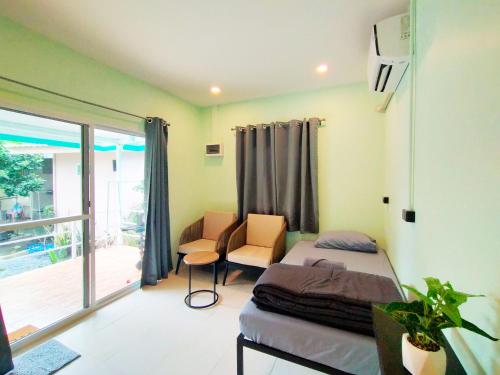 a bedroom with a bed and a chair and a window at Palm Garden house 1 close to Bang Tao beach in Ban Phak Chit
