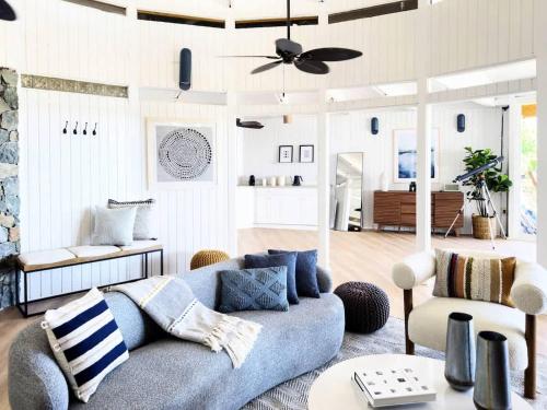 a living room with a blue couch and a ceiling fan at Luxury Oceanview Villa Walk to Beach & Dining in Enighed