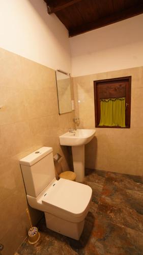 a bathroom with a white toilet and a sink at New Morning Hikkaduwa in Hikkaduwa