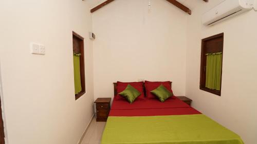 a bedroom with a bed with green and red pillows at New Morning Hikkaduwa in Hikkaduwa
