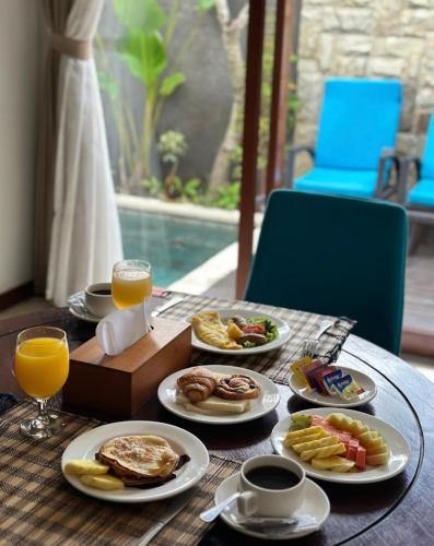 einen Tisch mit Teller mit Speisen und Orangensaft in der Unterkunft Sanata Luxury Villa in Canggu