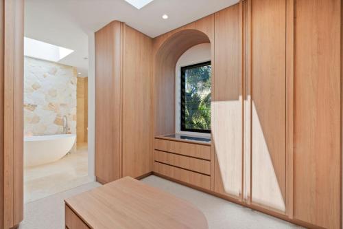 a bathroom with wooden cabinets and a tub and a television at Ebony Escape in Casuarina