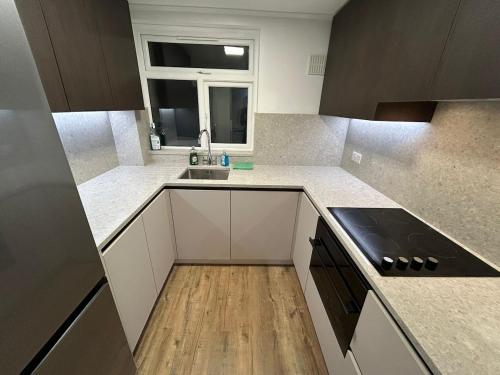 eine Küche mit weißen Schränken und einer Spüle und einem Fenster in der Unterkunft Luxury apartment in Guildford in Guildford