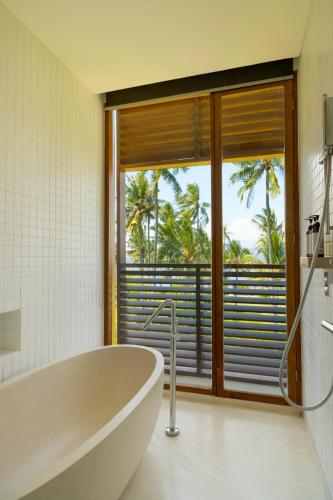 a bathroom with a tub and a large window at Dialoog Banyuwangi in Banyuwangi