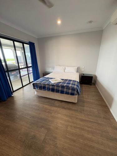 a bedroom with a bed in a room with wood floors at Reef Gardens Motel in Proserpine