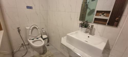 a white bathroom with a toilet and a sink at The time's pool villa in Ban Bung