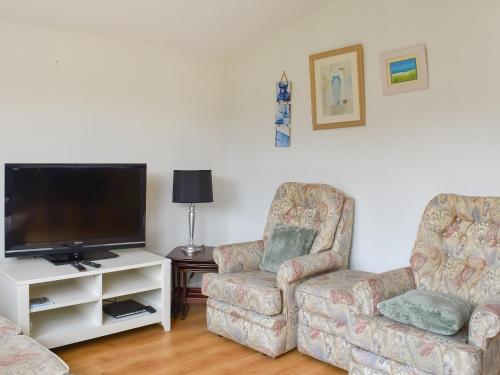 ein Wohnzimmer mit zwei Stühlen und einem Flachbildfernseher in der Unterkunft Mother Ivy's Bay - Uk47553 in Saint Merryn