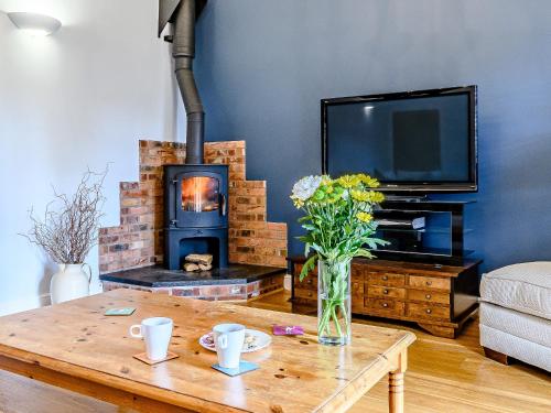 a living room with a wooden table with a fireplace at Low Barn in Market Bosworth