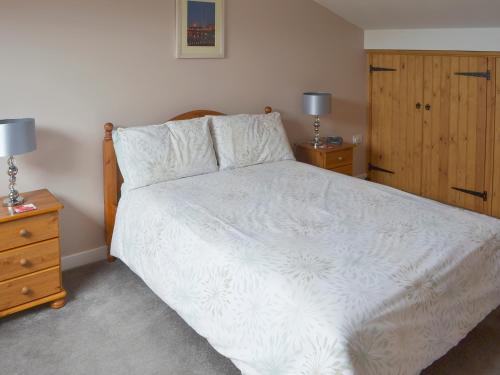 a bedroom with a white bed and two night stands at Clougha View - 29531 in Scotforth