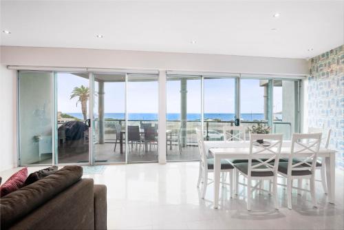 a living room with a table and chairs and a view of the ocean at Tidehouse - Scenic Esplanade Escape with Shared Pool in Victor Harbor