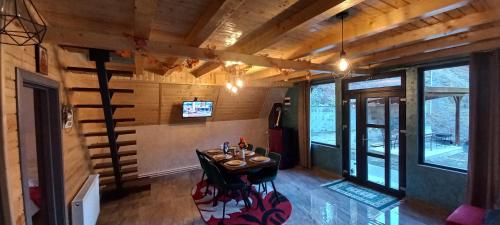 a dining room with a table in a room with wooden walls at Cabana Doi Brazi A-FRAME in Dămuc